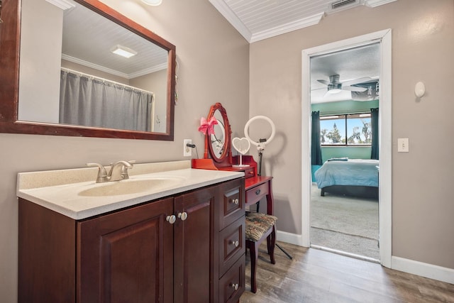 bathroom featuring ceiling fan, vanity, ornamental molding, and hardwood / wood-style flooring