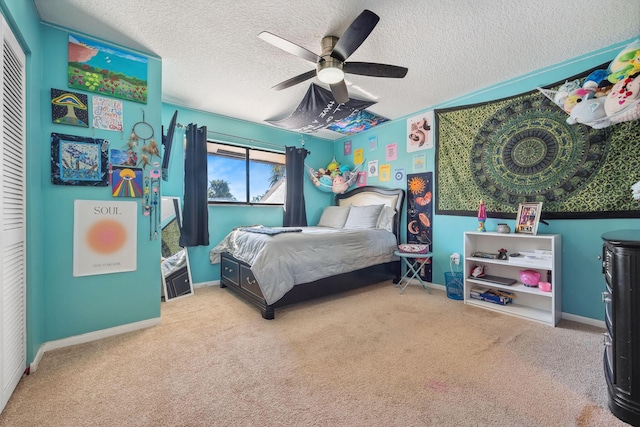 bedroom featuring a closet, a textured ceiling, ceiling fan, and light carpet