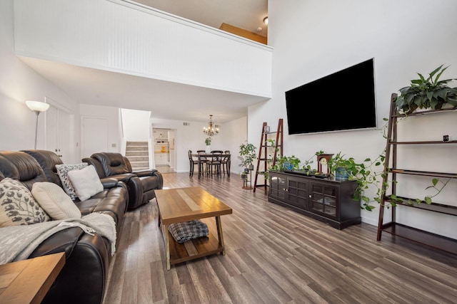 living room with a high ceiling, a notable chandelier, and wood-type flooring