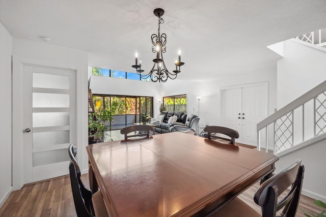 dining area featuring a textured ceiling, a notable chandelier, and wood-type flooring