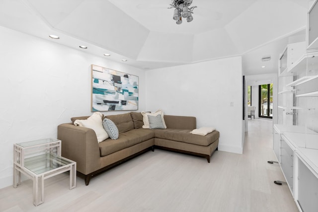 living room featuring a tray ceiling, ceiling fan, and light hardwood / wood-style floors