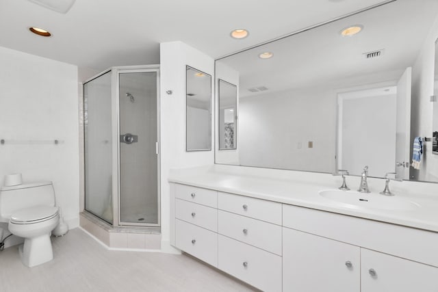 bathroom featuring vanity, toilet, and a shower with door