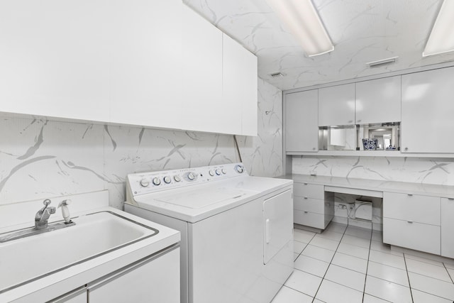 washroom with sink, light tile patterned floors, cabinets, and independent washer and dryer