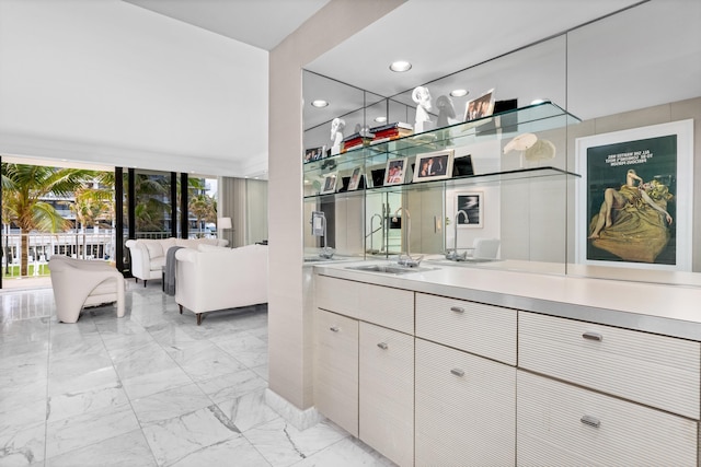 bar with white cabinets, a wall of windows, and sink