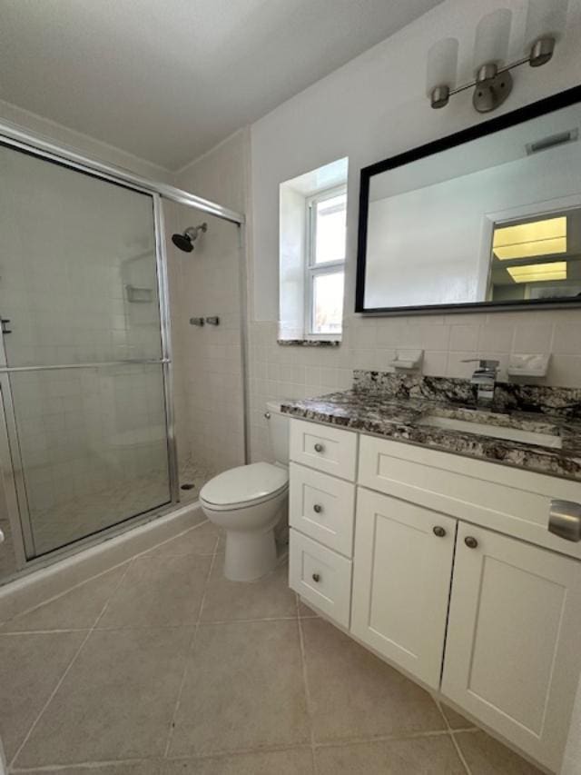 bathroom featuring backsplash, an enclosed shower, toilet, vanity, and tile walls