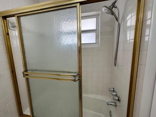 bathroom with combined bath / shower with glass door