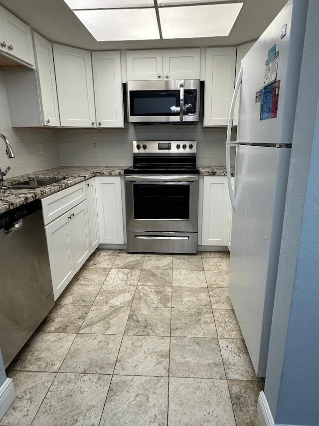 kitchen featuring dark stone countertops, sink, white cabinets, and appliances with stainless steel finishes