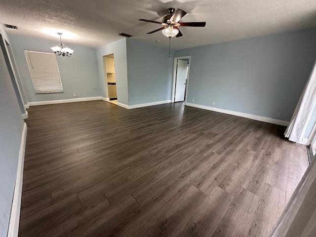 unfurnished living room with ceiling fan with notable chandelier, dark hardwood / wood-style flooring, and a textured ceiling