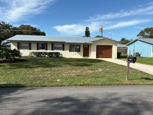 single story home with central AC, a garage, and a front lawn