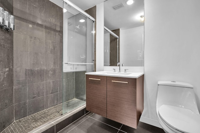 bathroom with tile patterned flooring, vanity, toilet, and a shower with shower door