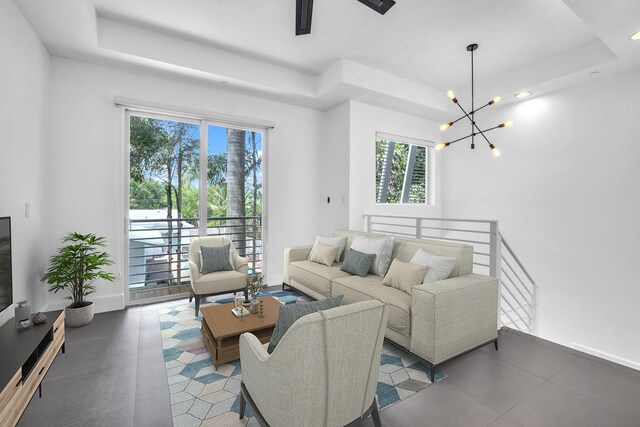 living room with a chandelier, a raised ceiling, and a wealth of natural light