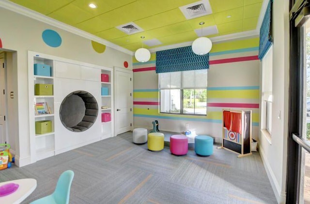 game room with a wealth of natural light, ornamental molding, and carpet flooring