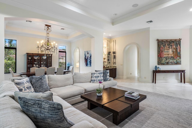 living room with ornamental molding, a chandelier, and a tray ceiling