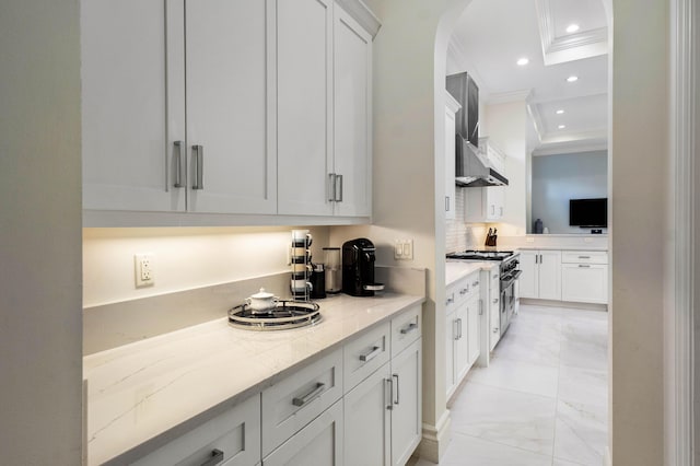 kitchen with stainless steel stove, tasteful backsplash, white cabinetry, ornamental molding, and light stone countertops