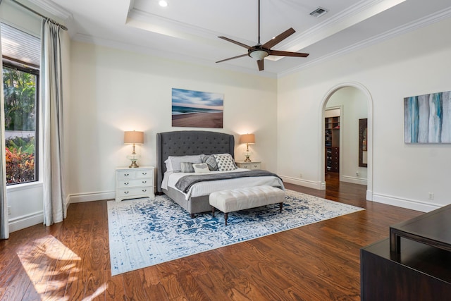 bedroom featuring dark hardwood / wood-style floors, ceiling fan, a tray ceiling, and crown molding