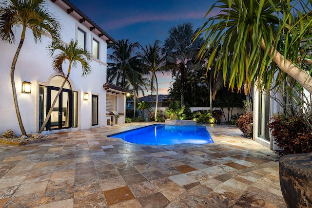 pool at dusk with a patio area and french doors