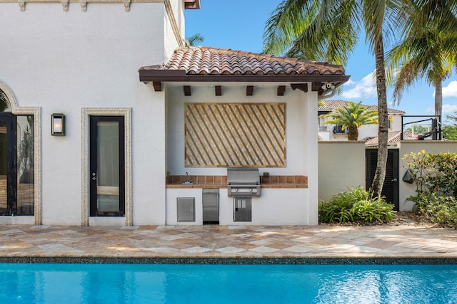 back of property featuring sink, a patio, and an outdoor kitchen