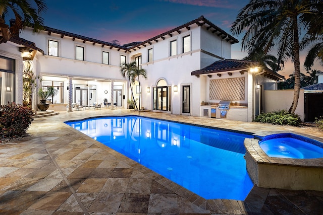 pool at dusk with an in ground hot tub and a patio area