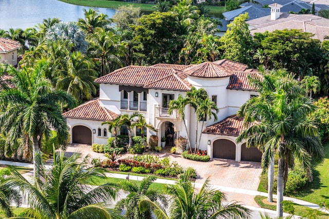 mediterranean / spanish house with a water view, a balcony, and a garage