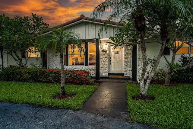 exterior entry at dusk featuring a lawn