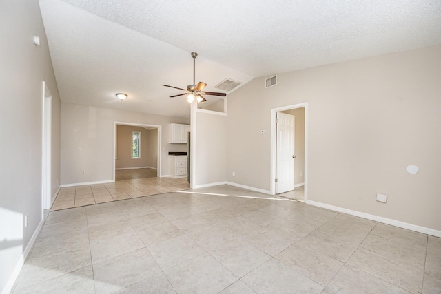 empty room featuring light tile patterned floors, a textured ceiling, vaulted ceiling, and ceiling fan