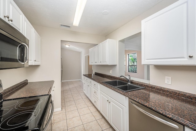 kitchen featuring white cabinetry, sink, a textured ceiling, light tile patterned floors, and appliances with stainless steel finishes