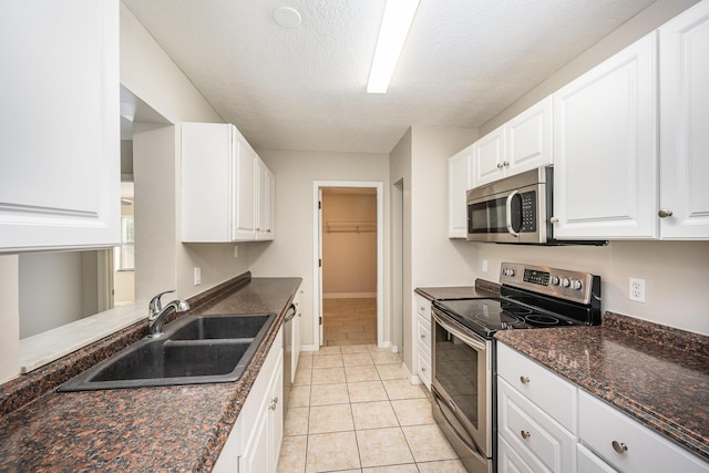 kitchen with white cabinets, sink, light tile patterned floors, and stainless steel appliances