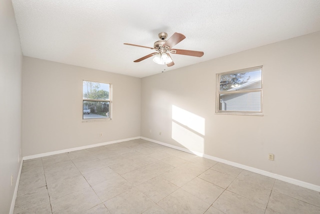 tiled empty room with ceiling fan and a textured ceiling