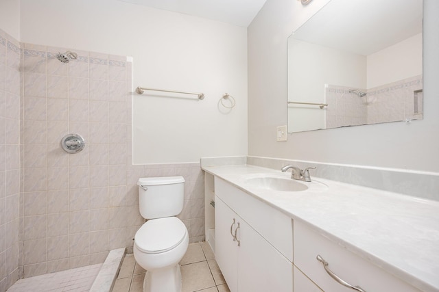 bathroom featuring a tile shower, tile patterned floors, toilet, vanity, and tile walls