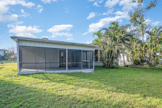 rear view of house with a lawn and a sunroom