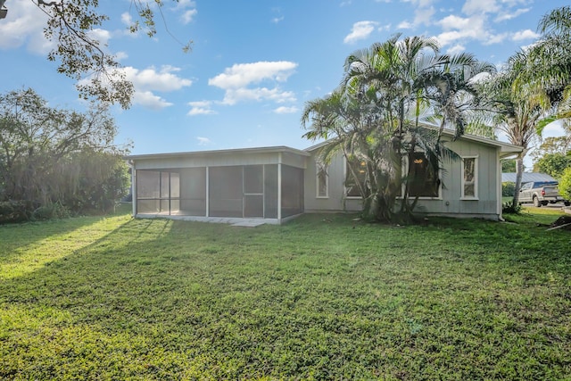 rear view of house with a lawn and a sunroom