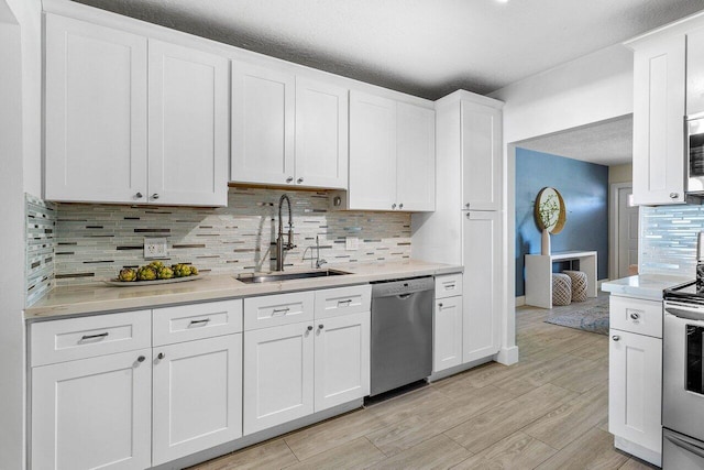 kitchen with tasteful backsplash, white cabinetry, sink, and stainless steel appliances