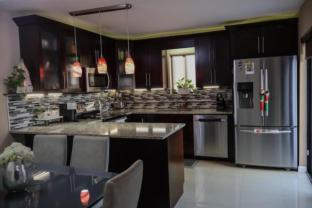 kitchen featuring sink, stainless steel appliances, light stone counters, pendant lighting, and light tile patterned floors