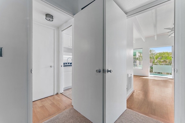 hallway with beamed ceiling and light wood-type flooring