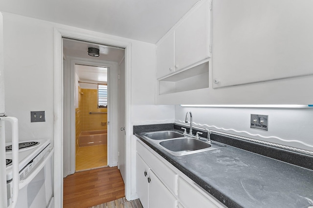 kitchen with light hardwood / wood-style flooring, white cabinetry, white electric stove, and sink