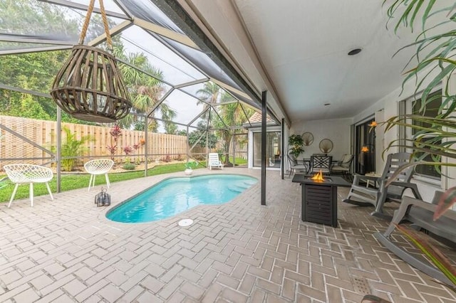 view of pool featuring glass enclosure, a patio, and a fire pit