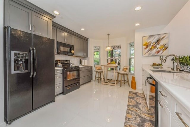 kitchen featuring white cabinetry, decorative light fixtures, light stone countertops, black appliances, and sink