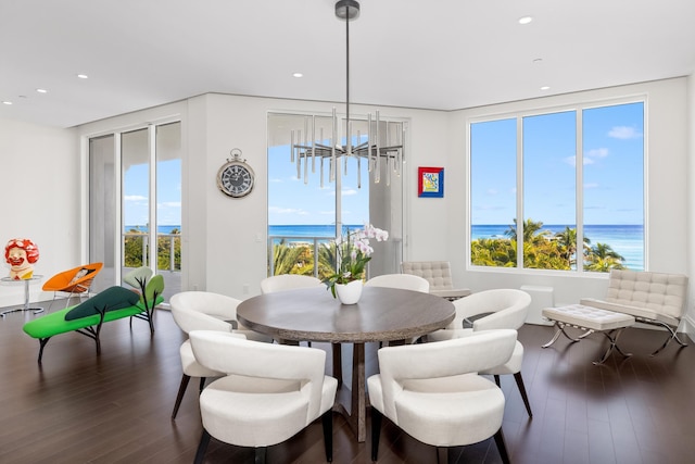 dining space featuring a chandelier, a water view, and dark wood-type flooring