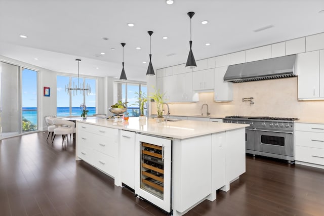 kitchen featuring high end range, a kitchen island with sink, a water view, wine cooler, and extractor fan