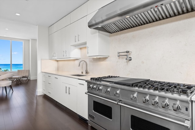 kitchen featuring a water view, range with two ovens, white cabinetry, and exhaust hood