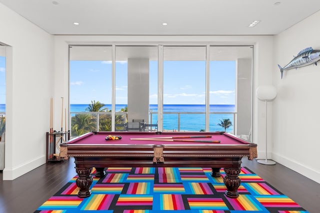 game room with dark hardwood / wood-style floors, a water view, and billiards