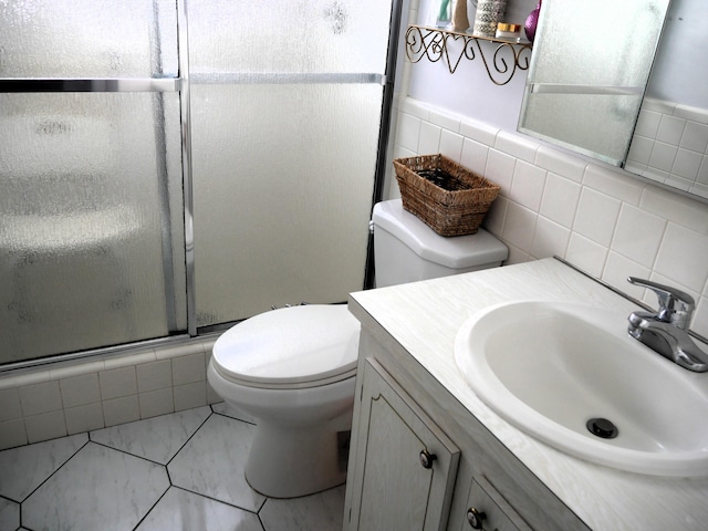 bathroom featuring toilet, a shower with door, backsplash, tile patterned flooring, and vanity