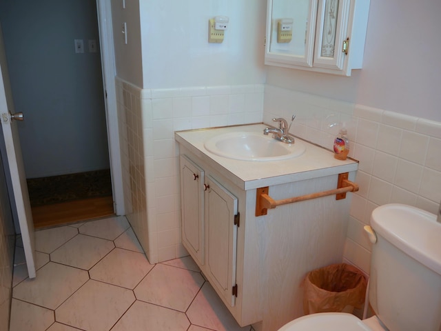 bathroom featuring toilet, vanity, tile walls, and tile patterned flooring