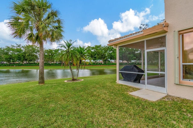 view of yard with a sunroom and a water view