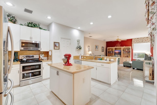 kitchen featuring a center island, sink, stainless steel appliances, kitchen peninsula, and white cabinets