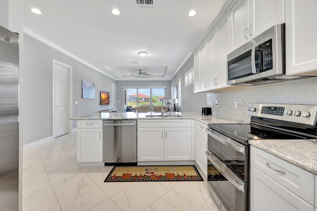 kitchen with sink, crown molding, appliances with stainless steel finishes, white cabinetry, and kitchen peninsula