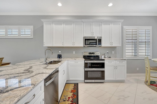 kitchen featuring appliances with stainless steel finishes, white cabinetry, sink, ornamental molding, and light stone countertops