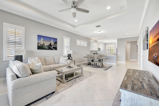 living room featuring ornamental molding, ceiling fan, and a tray ceiling