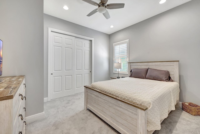 bedroom with light colored carpet, ceiling fan, and a closet