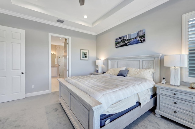 carpeted bedroom with ceiling fan, ensuite bath, ornamental molding, and a tray ceiling